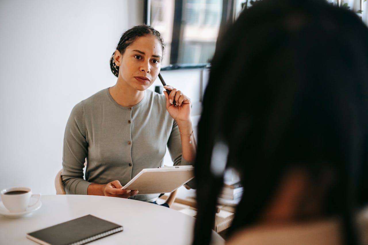 Therapist discussing with a client in a modern office setting. Focus on mental health support.